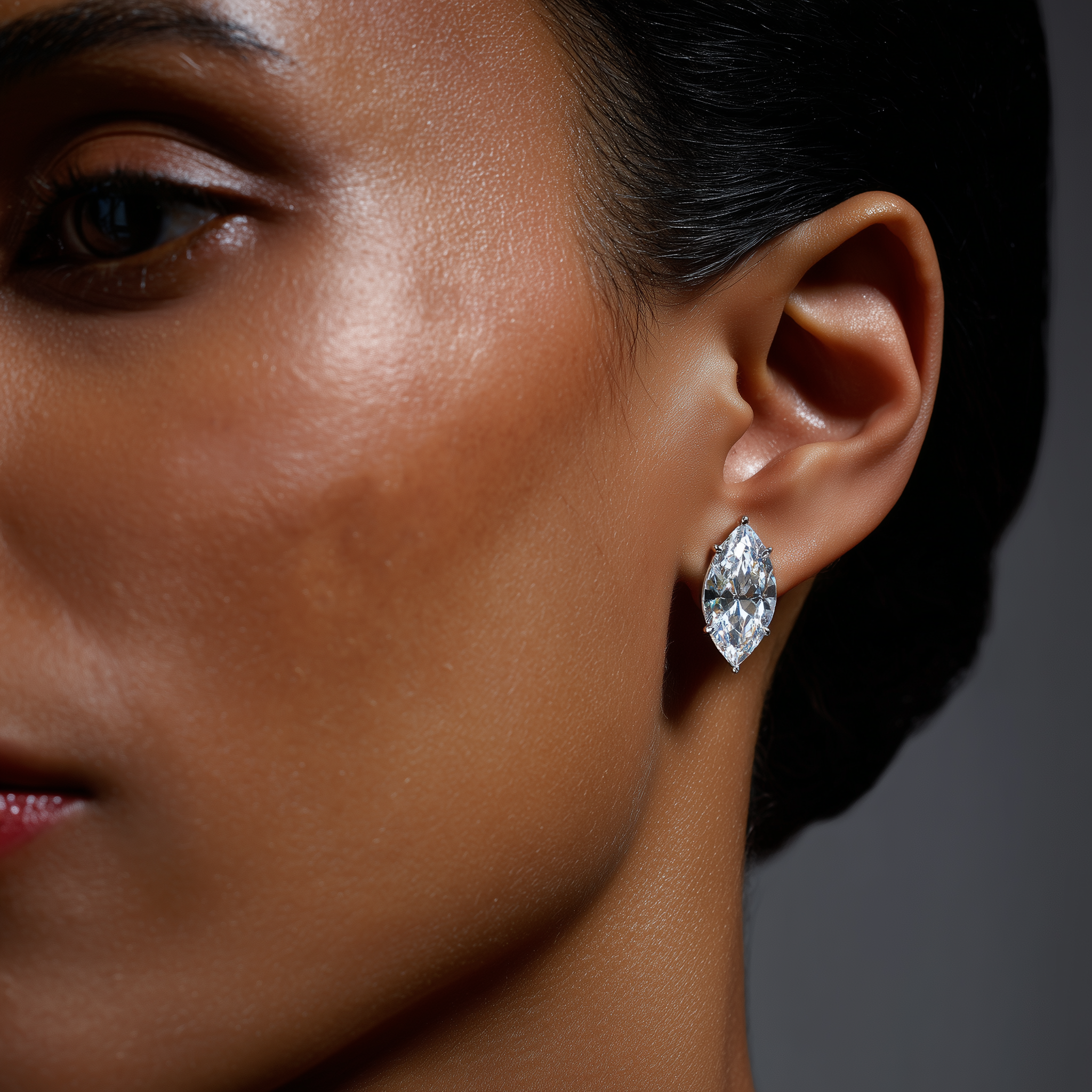 Close-up of a woman's ear wearing a diamond earring with a dark background
