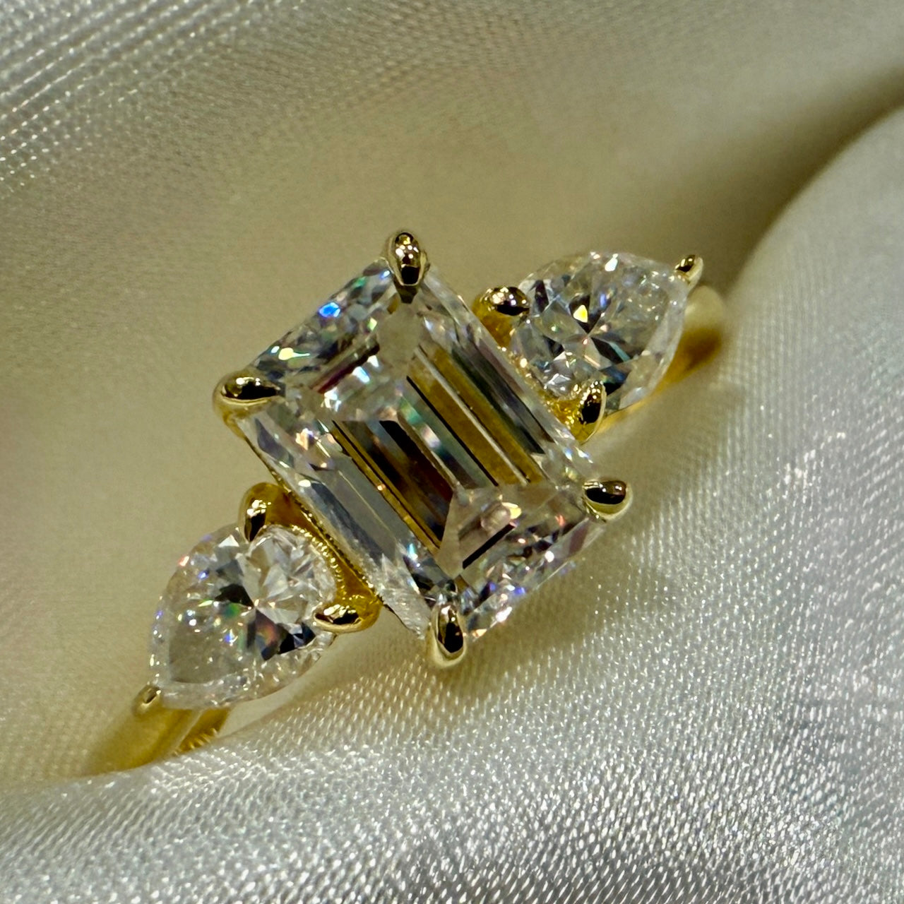 Gold ring with three diamond stones on a beige fabric background